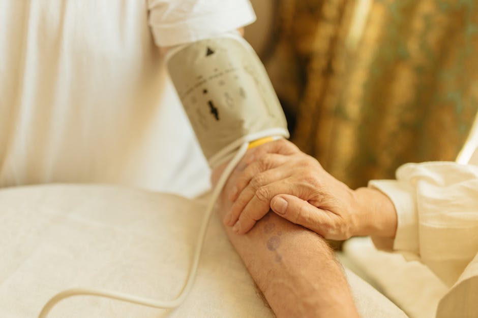 Close-up of a blood pressure measurement on a senior adult's arm indoors. Soft lighting.