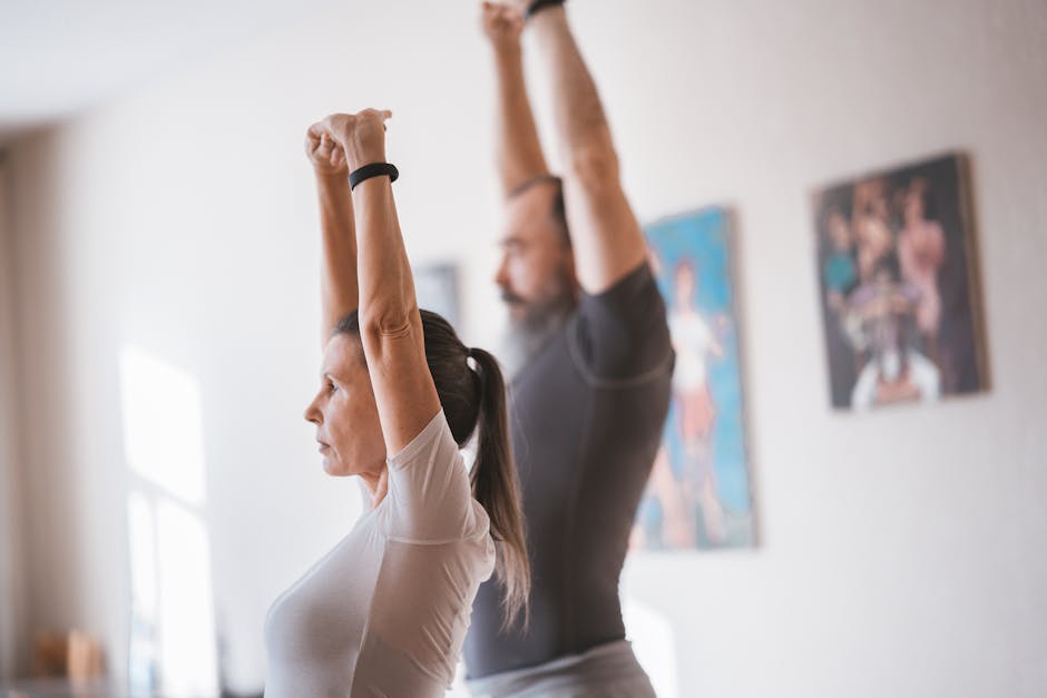 Elderly couple stretching together indoors for a healthy lifestyle routine.
