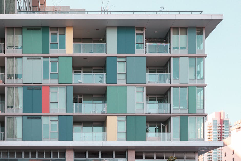 Vibrant modern apartment building facade with glass balconies under a clear blue sky.