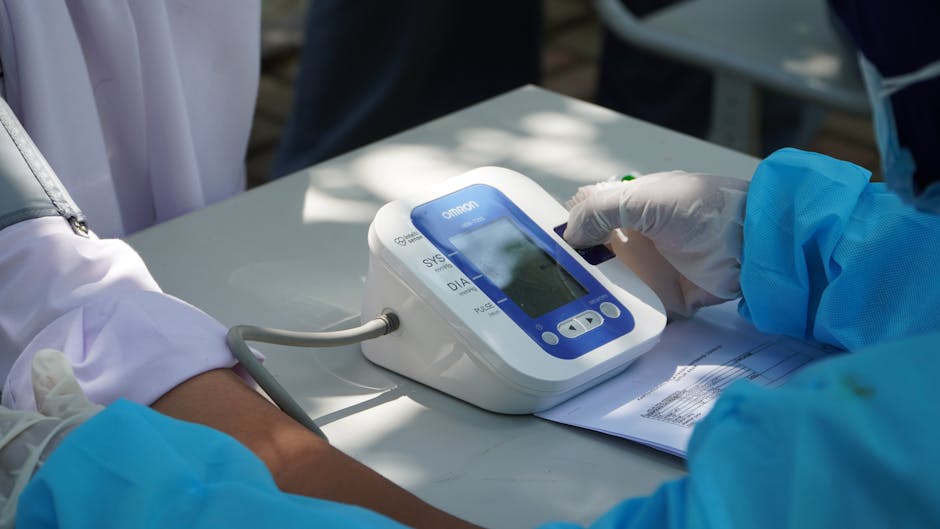 Healthcare worker checking patient's blood pressure with a digital device outdoors.