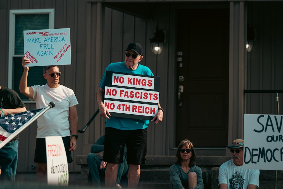 A group of adults protesting with political signs expressing various messages, emphasizing democracy and freedom.