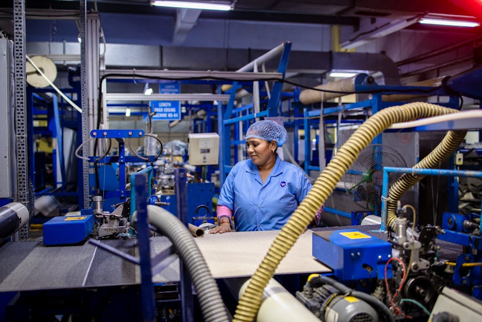 A female worker in a blue uniform operates machinery in a textile factory.
