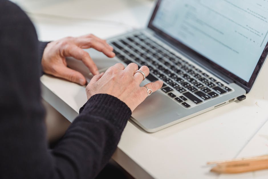Close-up of hands typing on a laptop keyboard in a home office setting. Ideal for business and technology themes.