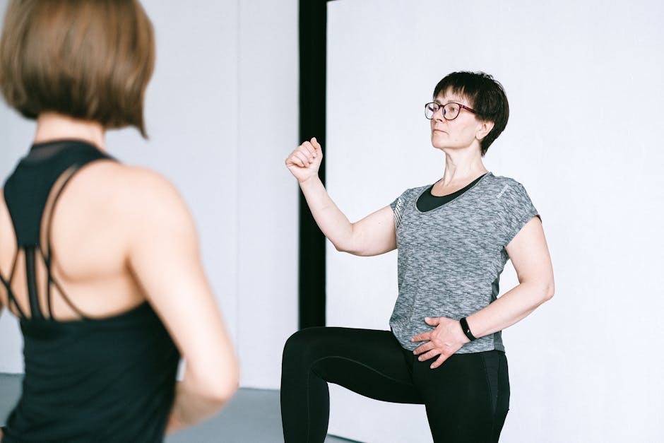 A woman practicing yoga indoors with a fitness instructor providing guidance.