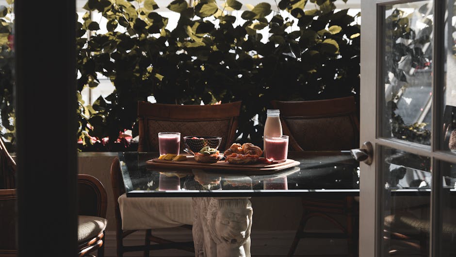 A cozy morning breakfast setup with smoothies and pastries on a sunlit table.