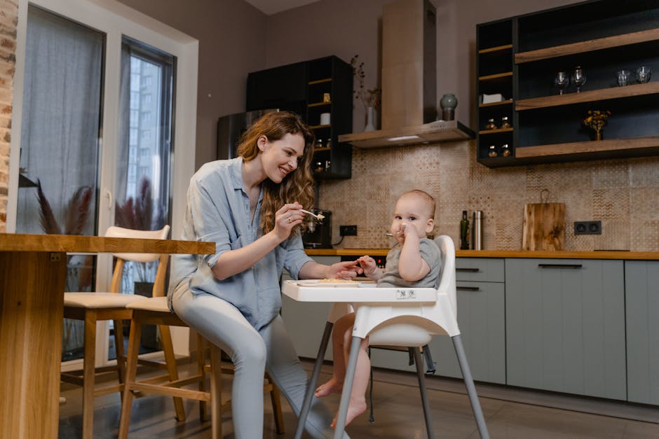 Mother feeding her baby in a modern kitchen, capturing a tender parenting moment.