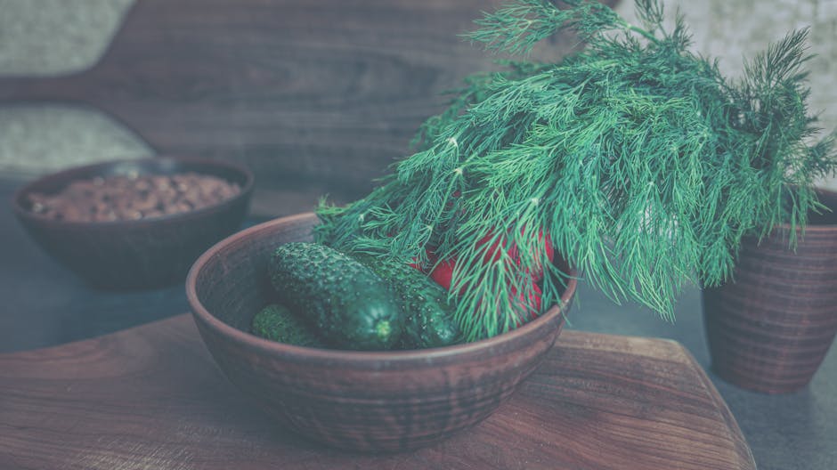 Fresh cucumbers and dill in a rustic wooden bowl, perfect for a healthy meal.