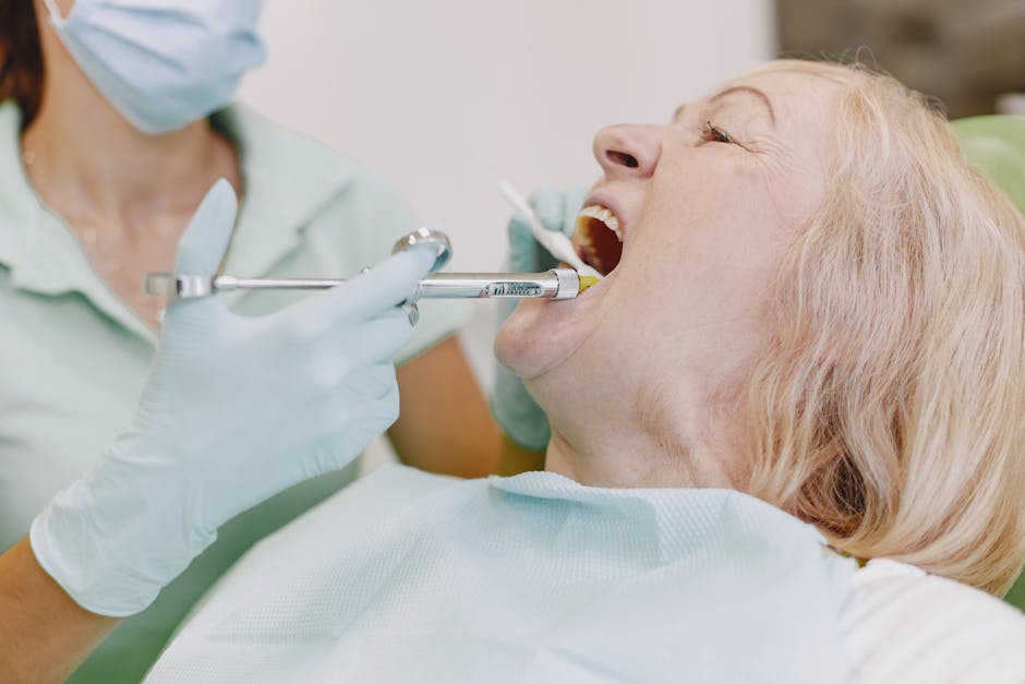 Senior woman undergoing dental examination with dentist using syringe and tools.