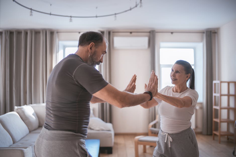 Elderly couple practicing joint exercises indoors, promoting health and fitness.