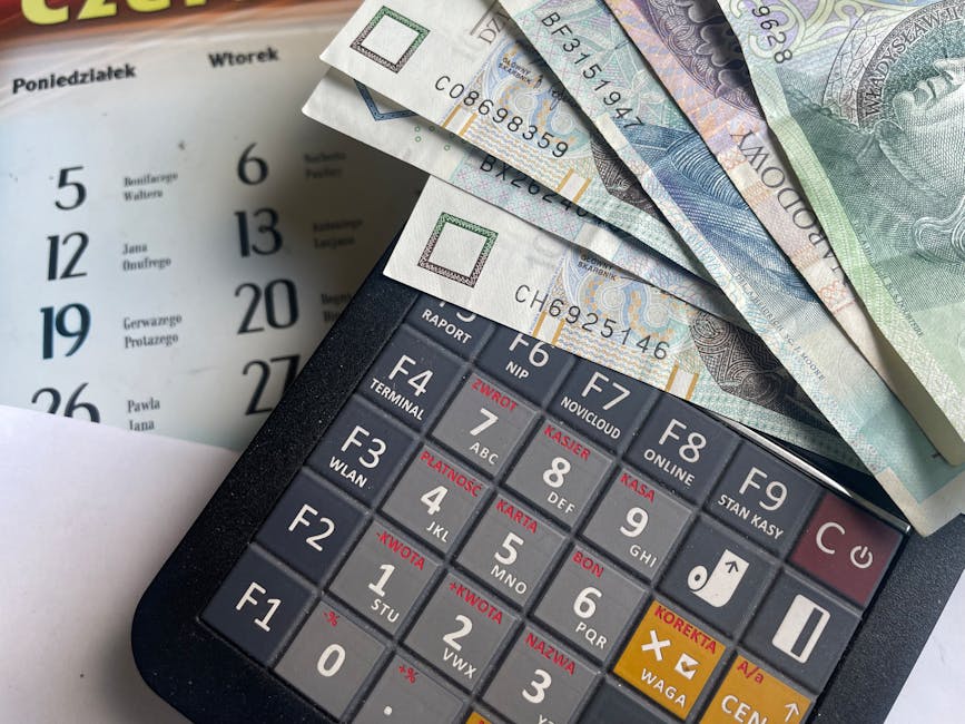 Close-up of Polish Zloty banknotes on a calculator with a calendar in the background.