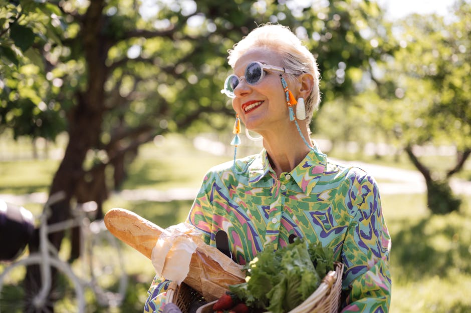 A joyful senior woman holding a basket with bread and vegetables in a sunny park.