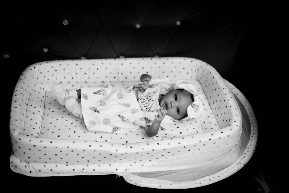 Black and white photo of a newborn baby lying in a comfortable crib.