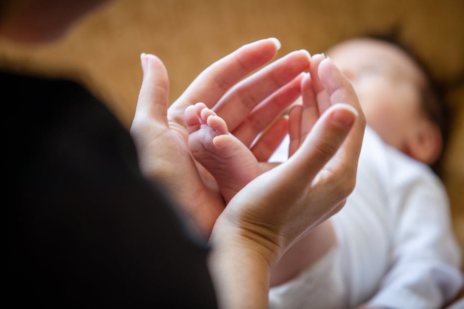 A mother's hands gently holding her newborn's feet, symbolizing love and care.