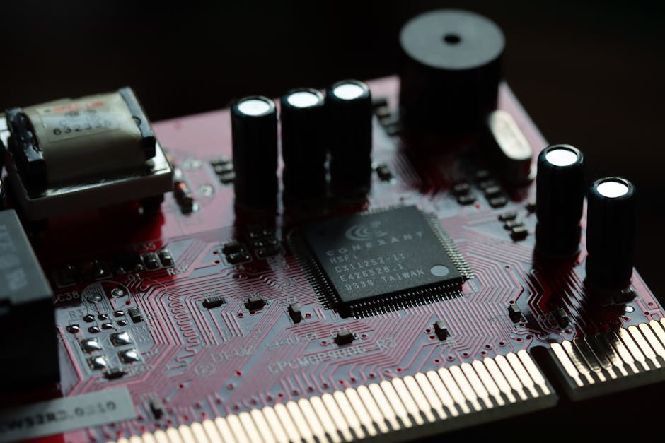 Detailed view of a red circuit board with various electronic components and microchip.