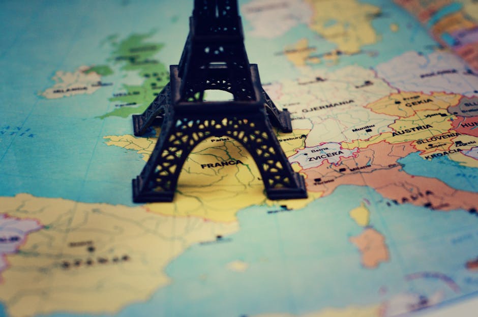 Miniature Eiffel Tower placed on a map of Europe, focusing on France.