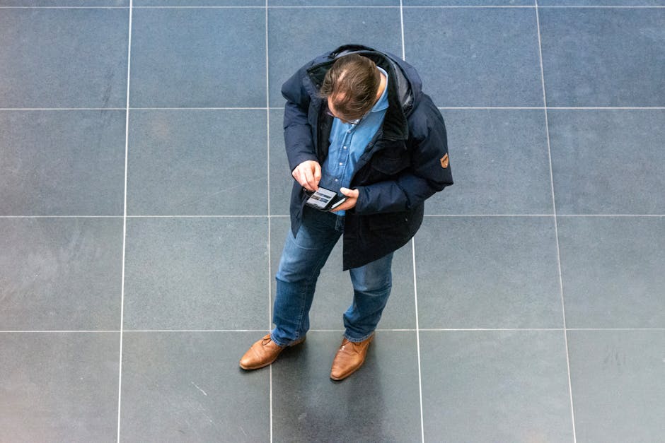 Overhead view of a casually dressed man looking at his phone indoors.