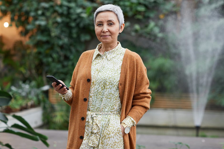 Senior woman with short hair using smartphone in an indoor greenhouse.