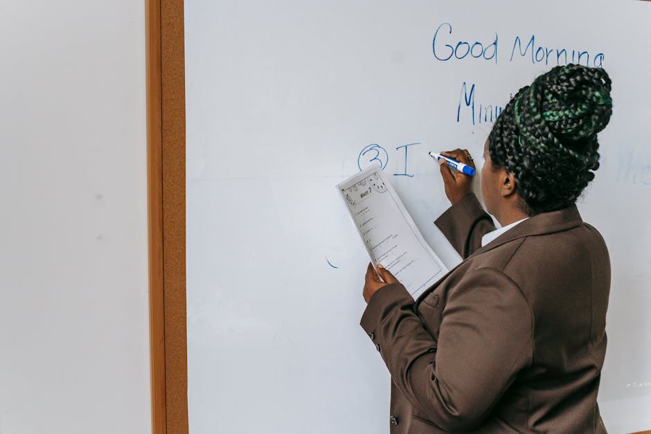 Back view anonymous African American female teacher wearing formal suit writing information on paper in auditorium