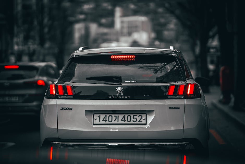 Rear view of a modern SUV on busy city streets, showcasing taillights and urban landscape.