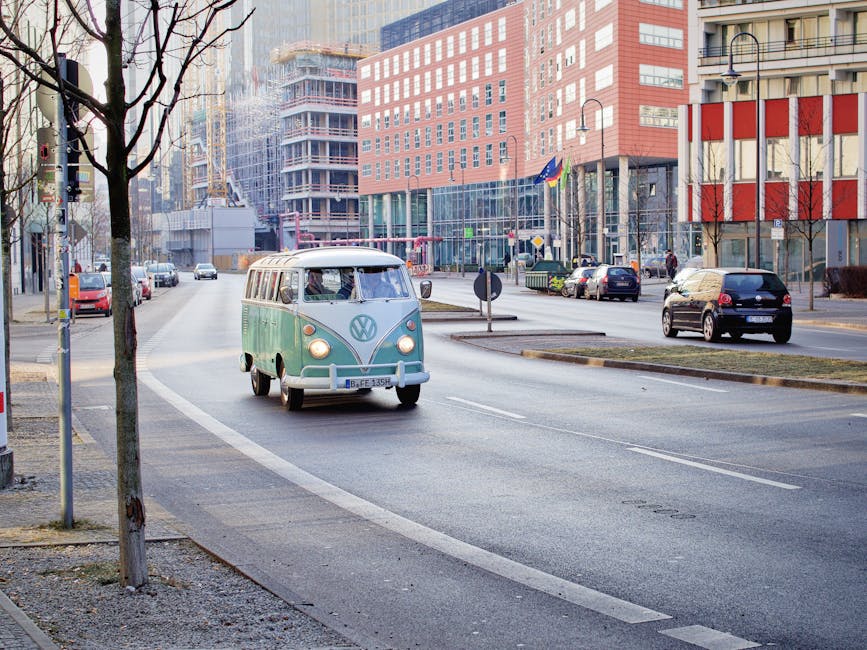 Vintage VW van driving through central Berlin, showcasing urban architecture and street life.