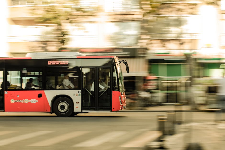 A dynamic photo of a red bus speeding through an urban street, capturing city life.