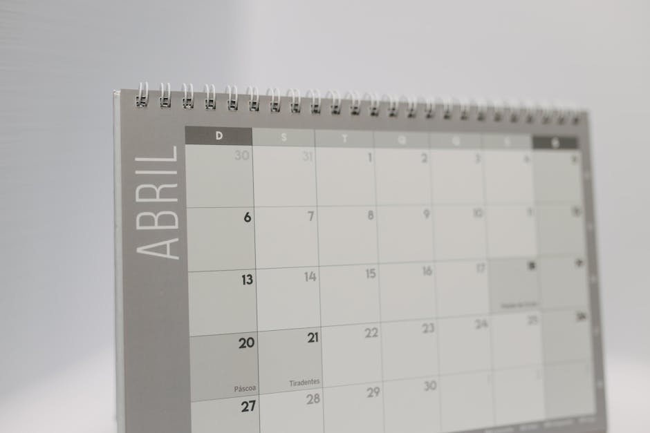 Close-up of a spiral-bound April desk calendar with a gray minimalistic design.