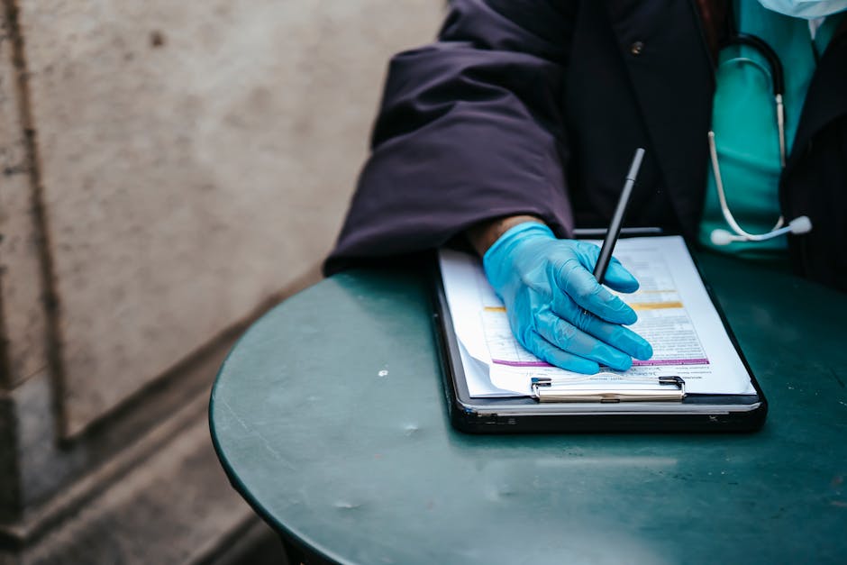 Crop anonymous ethnic female physician in disposable glove with paper on clipboard working at table in daylight