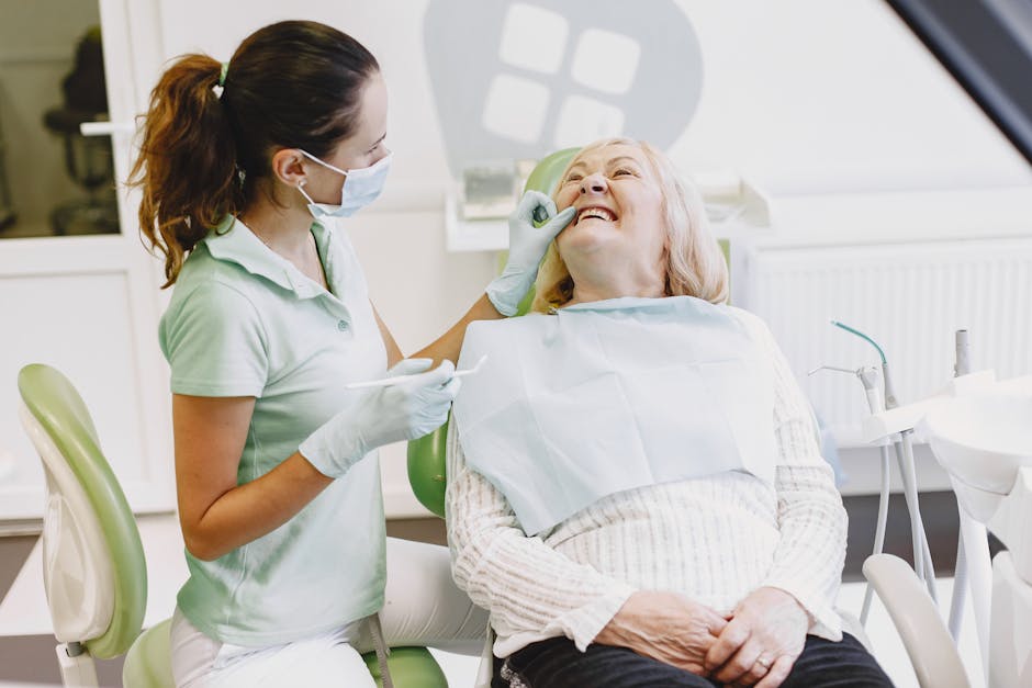 A female dentist examining a senior woman in a dental office. Both are smiling.