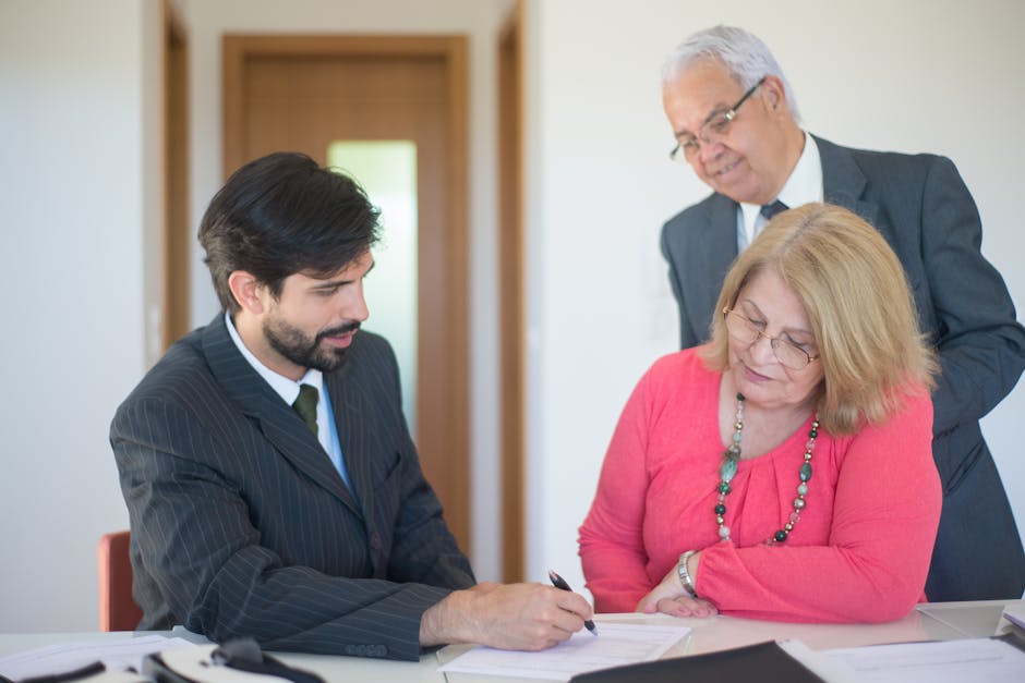 Senior couple signing real estate documents with an agent in a modern office setting.
