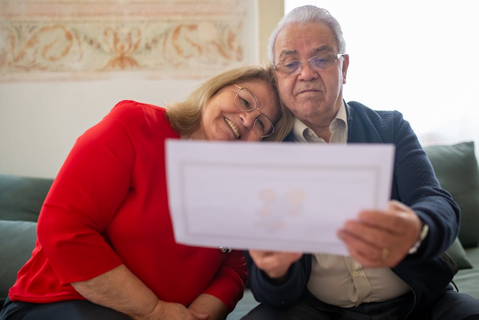 An elderly couple happily reviews a document while sitting comfortably together on a sofa.