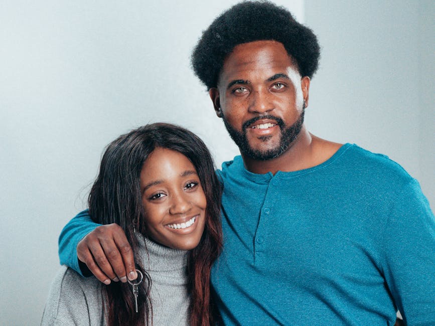 Smiling African American couple holding keys, celebrating home ownership.
