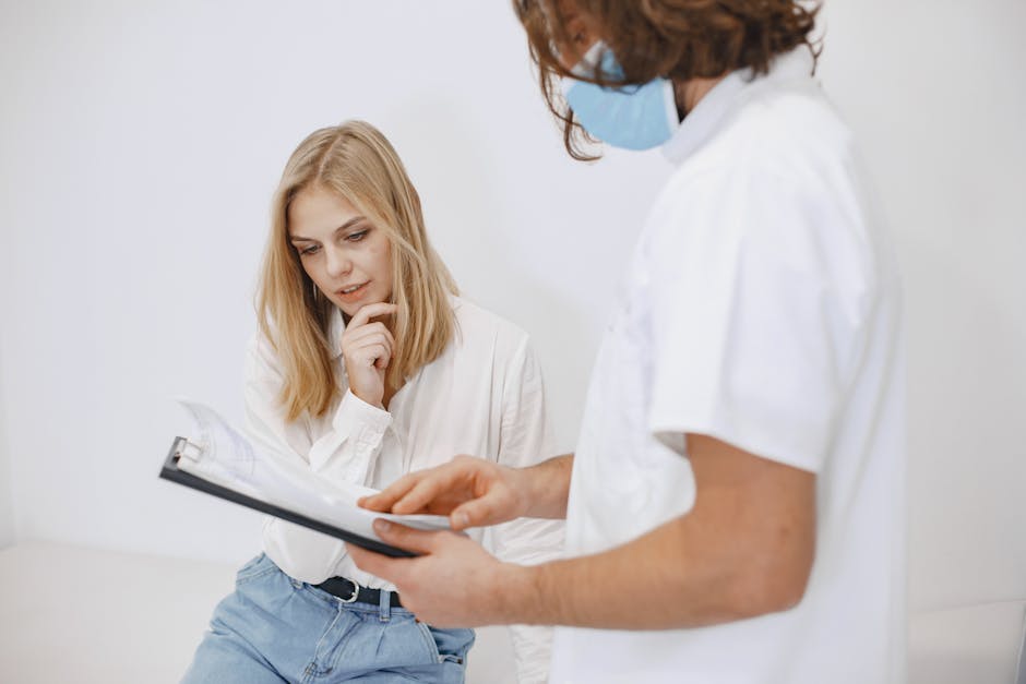A doctor in a face mask discusses diagnosis with a patient in a clinic setting.