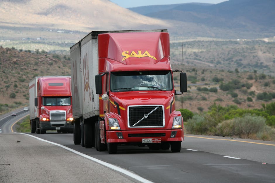 Red trucks driving through a scenic desert landscape showcasing transportation logistics.