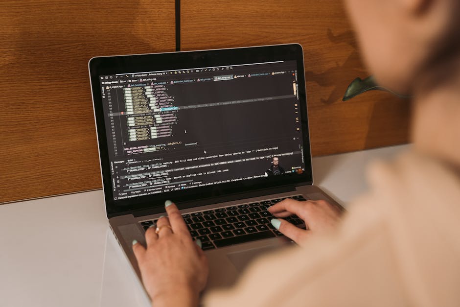 Close-up of a woman coding using a laptop in an office environment, showcasing modern technology.