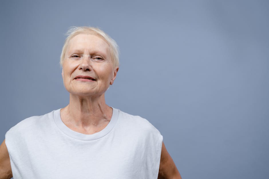 Senior woman with a gentle smile in a minimalist studio portrait, evoking warmth and positivity.