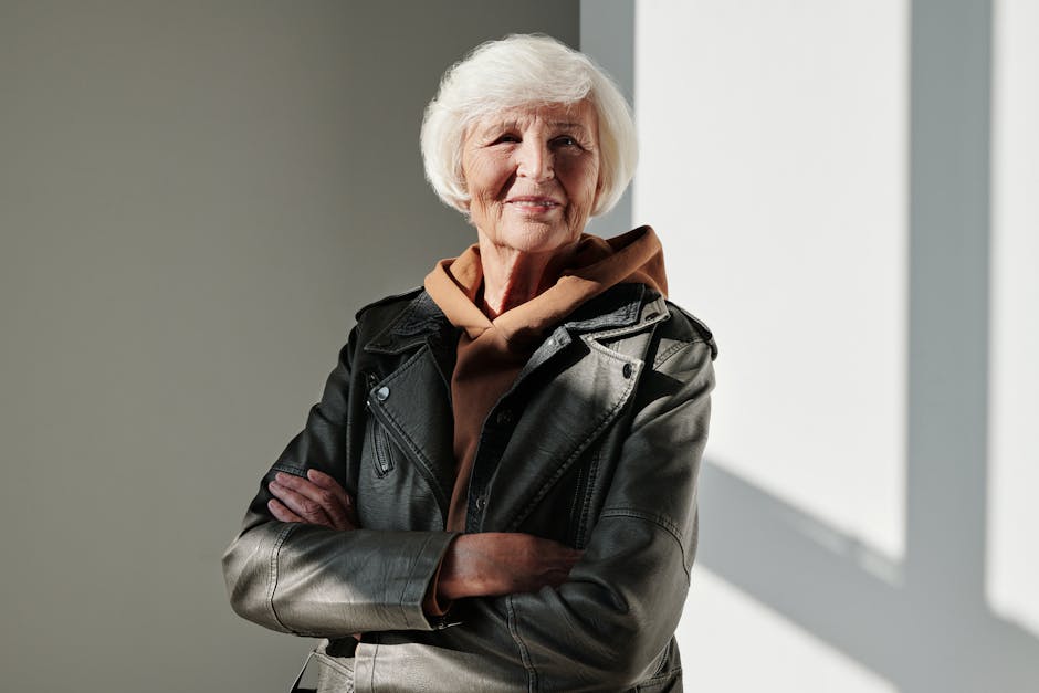 A senior woman exudes confidence and style in a black leather jacket with a warm smile.