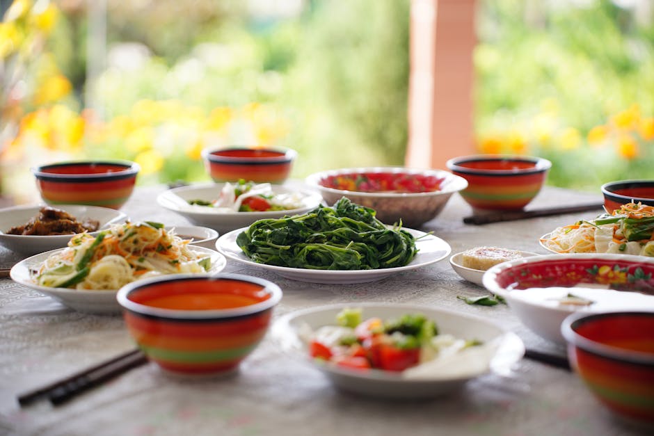 Tablescape of fresh Asian salads and vegetables outdoors, colorful bowls accent the setting.