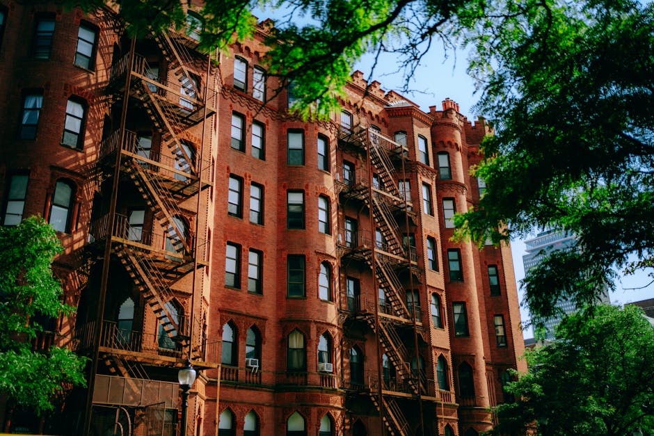 Traditional red brick building with metal fire escapes in an urban setting.