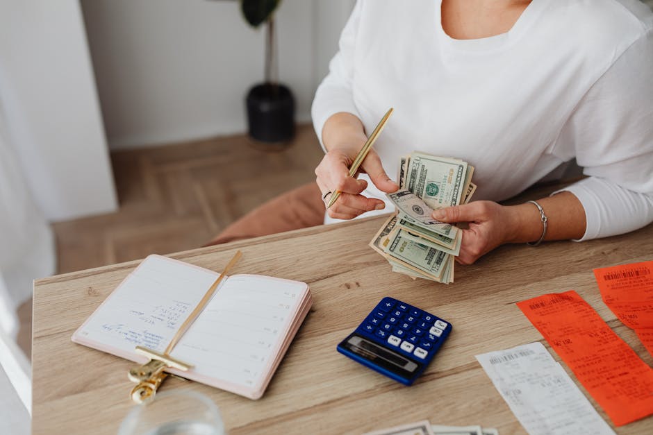 Woman sorting finances with a calculator, cash, and receipts at a desk.