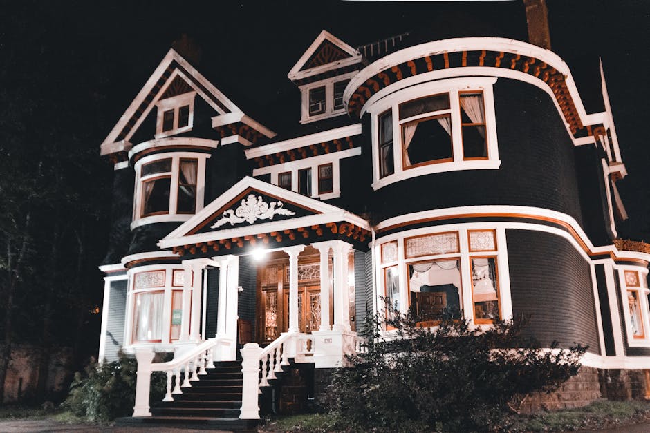 Capture of a grand Victorian mansion exterior illuminated at night, showcasing intricate architectural details.