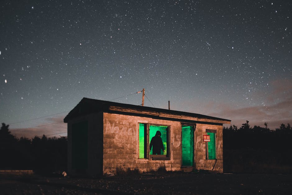 A small house with green light under a starry sky, creating a mysterious ambiance.