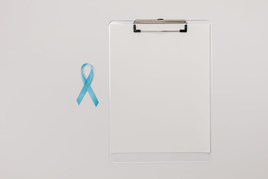 Flat lay of a blue prostate cancer awareness ribbon and a clipboard symbolizing health check-ups.
