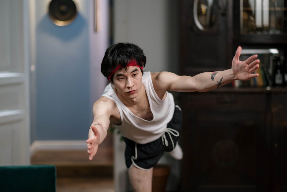 Asian man practicing yoga indoors, focusing on balance and healthy lifestyle during a home workout.