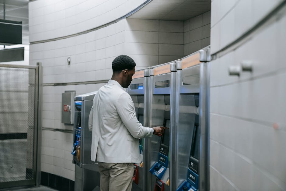 A man operating a ticket machine in a modern subway station, symbolizing urban public transport.