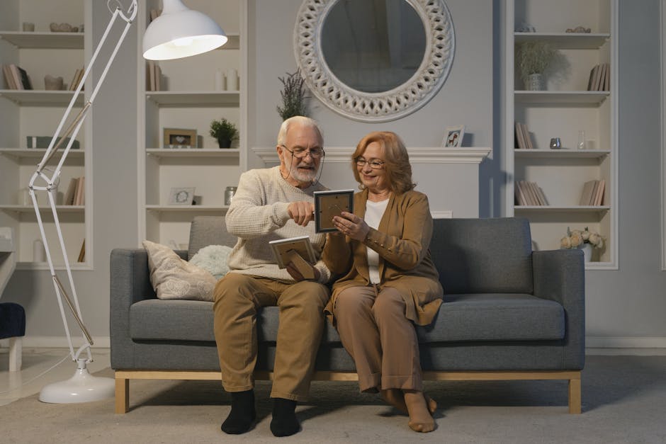 An elderly couple happily sitting on a couch, sharing cherished photo memories in a cozy living room.