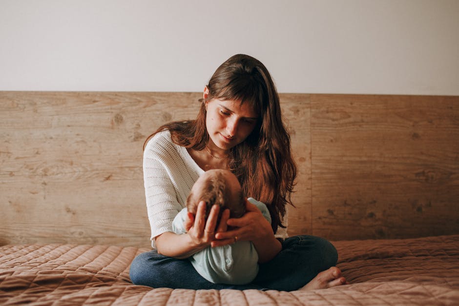 A loving mother cradles her baby on a bed, showcasing tender family moments indoors.
