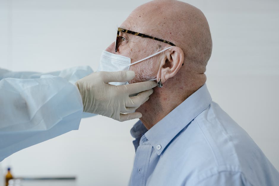 Side view of bald man with glasses wearing a face mask during a medical checkup.