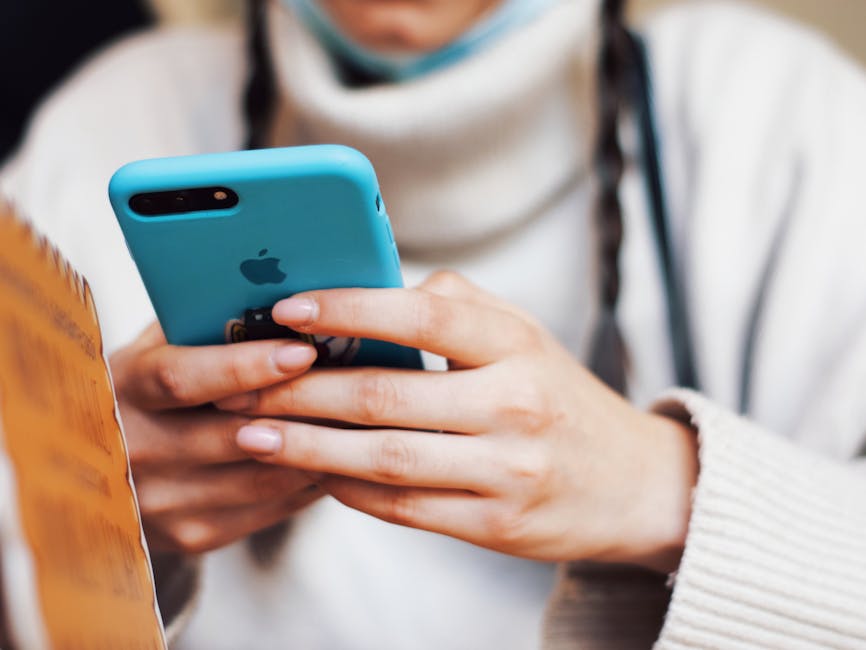 A person texting on a smartphone with a blue case indoors.