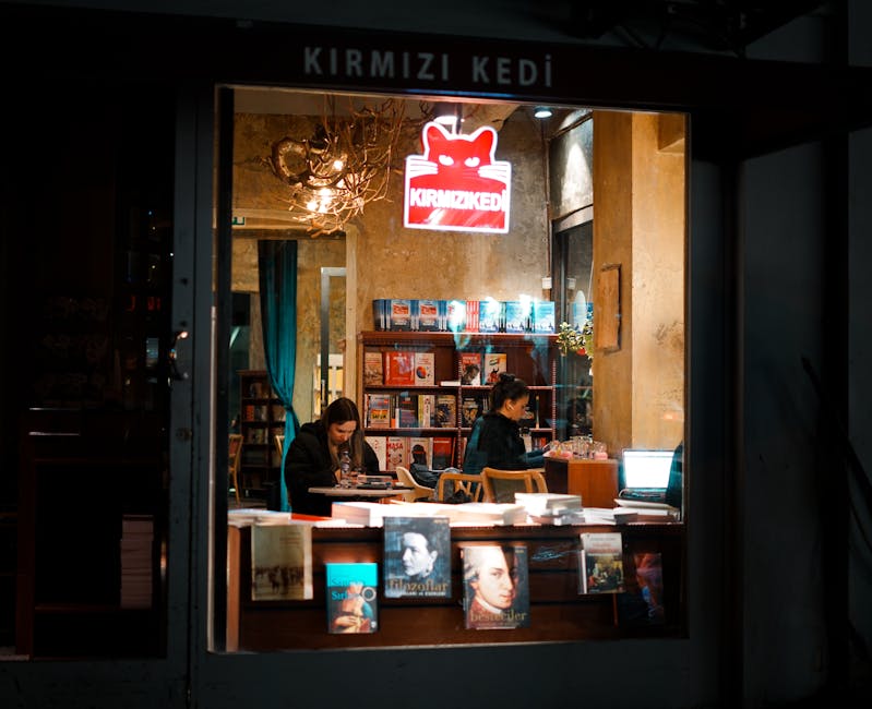 Warm and inviting view through a bookstore window at night with people reading.