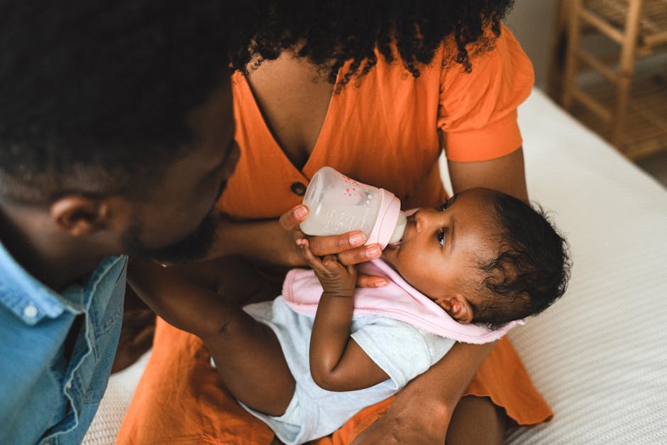A tender family moment as parents lovingly feed their baby with a bottle.